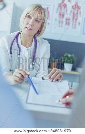 Doctor And Patient Examining A File With Medical Records, She Is Sitting On A Wheelchair