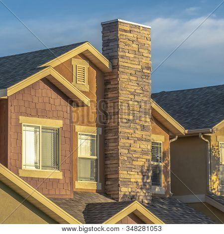 Square Frame Sunny Day View Of Home Facade With Stone Brick Chimneys And Gable Roofs