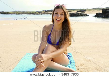 Happy Excited Girl In Blue Bikini On A Tropical Beach. Beautiful Girl Sitting On Beach Towel On Cale