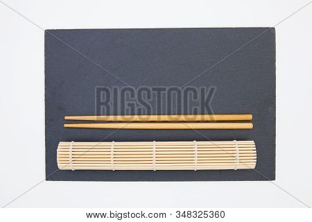 Rectangular Slate Plate With Chopsticks, Bamboo Mat  For Sushi On The White Table. Food Design