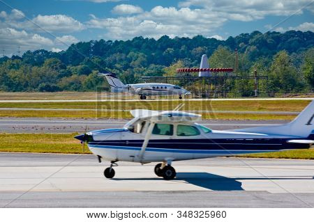 A Propeller Plane Taxiing For Takeoff While A Jet Is Landing In The Distance. Focus On Jet