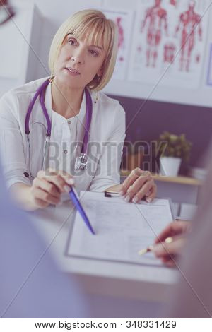 Doctor and patient examining a file with medical records, she is sitting on a wheelchair