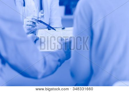 Doctor and patient examining a file with medical records, she is sitting on a wheelchair