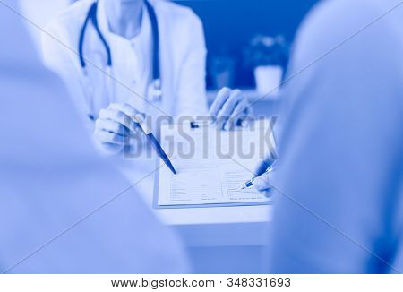 Doctor and patient examining a file with medical records, she is sitting on a wheelchair