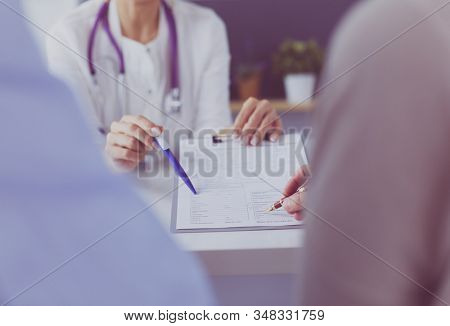Doctor and patient examining a file with medical records, she is sitting on a wheelchair