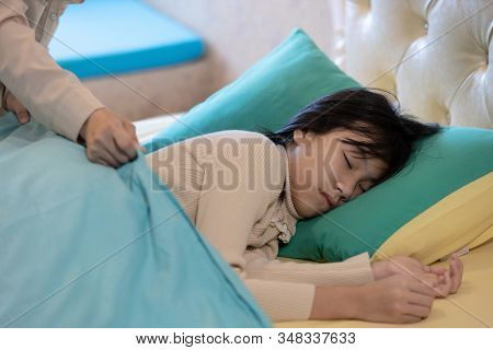Asian Child Girl Is Sleeping On A Bed In Bedroom,mother Putting Up The Blanket On Her Beautiful Daug
