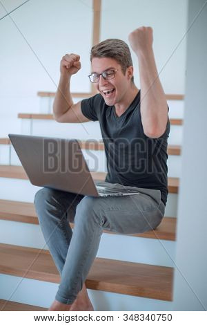 close up. happy young man with laptop sitting on steps