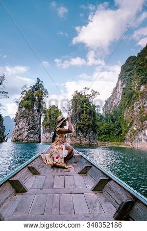 Couple Traveling By Boat Exploring Epic Limestone Cliffs In Huge Lake In Khao Sok National Park, Chi