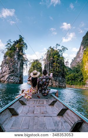 Couple Traveling By Boat Exploring Epic Limestone Cliffs In Huge Lake In Khao Sok National Park, Chi