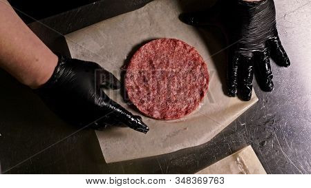 Cook Makes Meat Medallions For Burgers. Chef In Black Food Gloves Makes Cutlet. Cutlets Are Leveled 