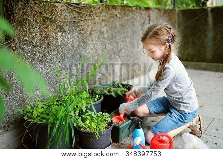 Cute Little Girl Helping In A Garden. Child Taking Part In Outdoor Household Chores.