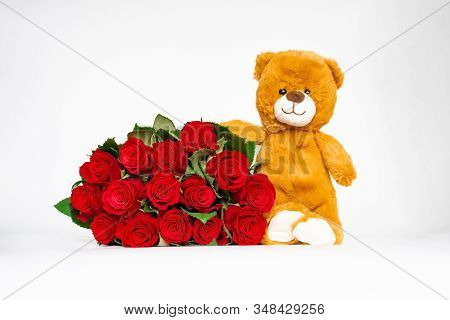 Selective Foucus Beautiful Red Roses Bouquet And Green Leaves With Blur Cute Tiny Brown Bear On Whit