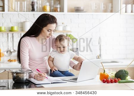 Hard Work With Baby. Busy Woman Trying To Note Down Project, Sitting With Fidgety Toddler, Empty Spa