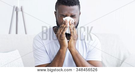 Seasonal Flu. Black Man Suffering From Snotty Nose At Home, Panorama