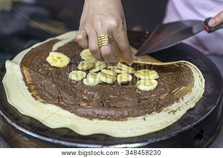 Thai Pancakes Preparation: The Chef Wraps A Pancake With Chocolate Paste And Banana With A Spatula, 