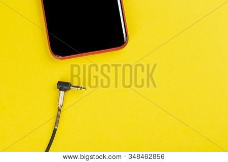 Close-up Jack Plug And A Cable With Phone On A Yellow Background, Top View.