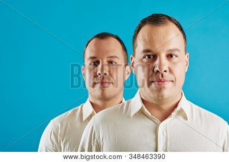 Conceptial Portrait Of Young Adult Caucasian Man Wearing White Shirt Standing Behind His Twin Brothe