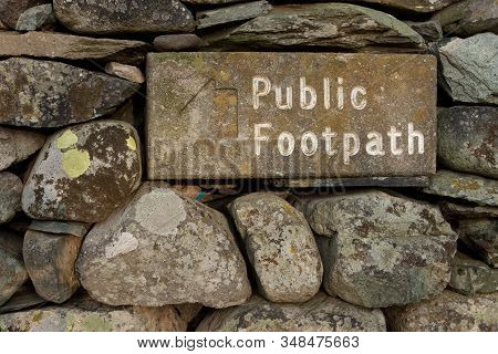 Stone Public Footpath Sign.  The Stone Public Footpath Sign Is Embedded In A Dry Stone Wall And Is S