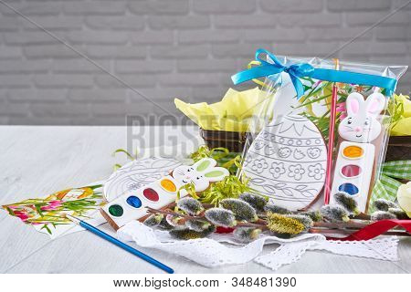 Front View Of Gift Painting Set For Coloring Easter Coocies In Shape Of Eggs, Isolated On Wooden Tab