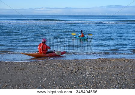 Unidentified People In Kayaks Going In To Water On North Sea Sandy Beach During Low Tide Near Castri
