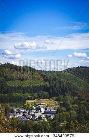 A Landscape Potrait Of A Sunny Day With A Blue Sky With Some Clouds Above A Village Surrounded By A 