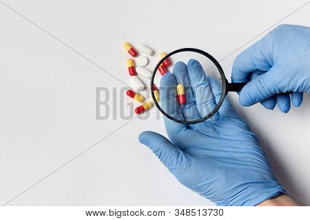 Concept - Pharmaceutical Testing, Drug Testing, Magnifying Glass, Pills On A White Background. Anti-