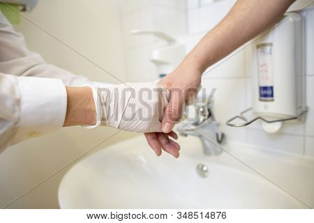 Nurse Disinfects A Patients Hand At A Sink