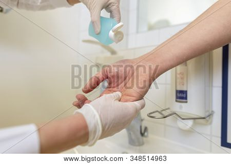 Nurse Disinfects A Patients Hand At A Sink