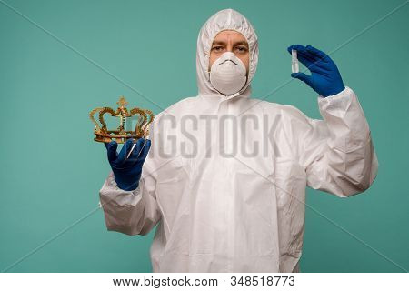 A Male Doctor In Protective Overalls And A Mask Holds An Ampoule With A Vaccine And Crown In His Han