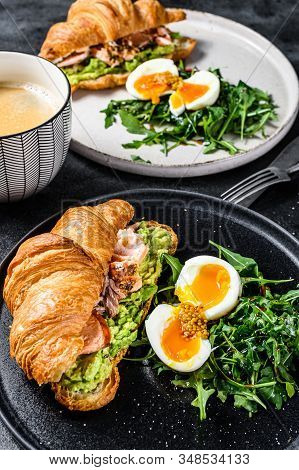 Croissant With Hot Smoked Salmon, Avacado, Arugula And Egg. Black Background. Top View