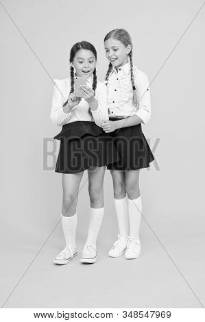 Girls School Uniform Using Smartphone. Schoolgirls Use Mobile Phone Or Smartphone To Share Photos. S