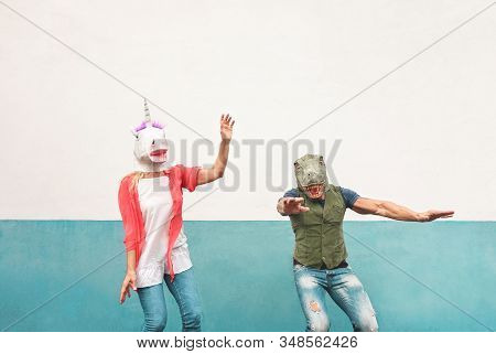 Happy Crazy Couple Dancing While Wearing T-rex And Unicorn Mask Outdoor - Seniors Having Fun Celebra