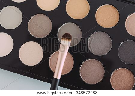 Close-up Of Brush On Top Of Eyeshadow Palette With Trendy Nudes And Bronzy Tones