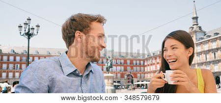Couple drinking coffee at Madrid cafe dating laughing panoramic banner. Two tourists peaple having fun conversation talking on outdoor Plaza Mayor terrace summer travel vacation. Young woman and man.