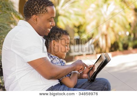 Heureux African American père et fils de Race mixte ayant amusant à l'aide de Touch Pad ordinateur tablette à l'extérieur.