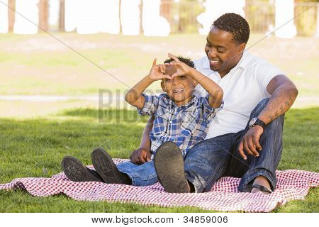 Feliz African American pai e filho de raça mista, fazendo sinal de mão do coração no Parque.