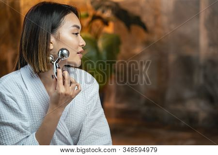 Asian Woman Using Modern Massagers For Facebuilding
