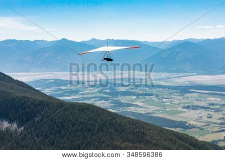 Back View Of Person Hang-gliding. Professional Air Sportsman Enjoying His Recreational Journey To Cr