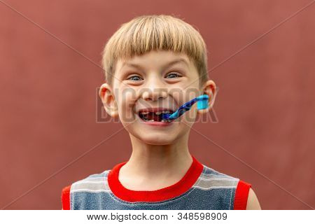 Joyful Child With A Toothbrush In His Mouth Wide Open Looking At The Camera