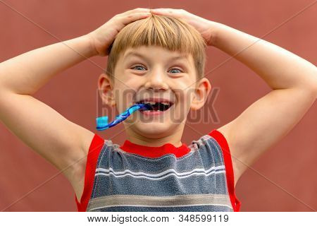 Joyful Child With A Toothbrush In His Mouth Wide Open Looking At The Camera