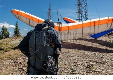 A Young Extremal Guy Preparing And Double-checking His Special Equipment And Gears For A Hang Glidin