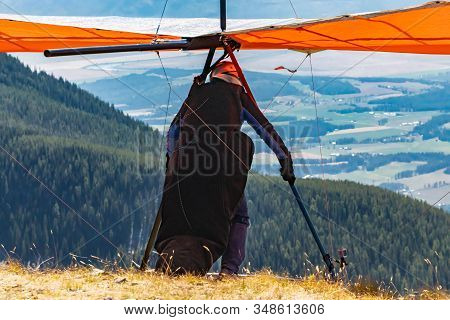 Man With Hang-glider Getting Ready To Fly From The Top Of Mountain Hill. Paraglider At The Top Of Th