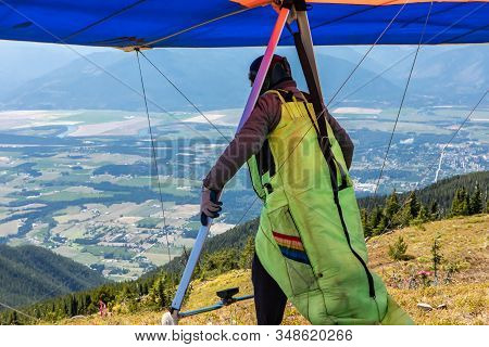 Man With Hang-glider Getting Ready To Fly From The Top Of Mountain Hill. Paraglider At The Top Of Th