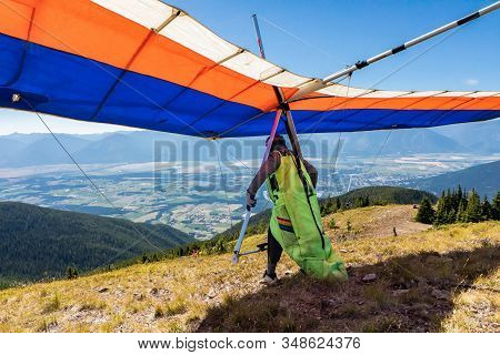 Hang Glider Preparing To Take Off From Mountain Top Hill. Kootenay Valley Mountains In Background, C