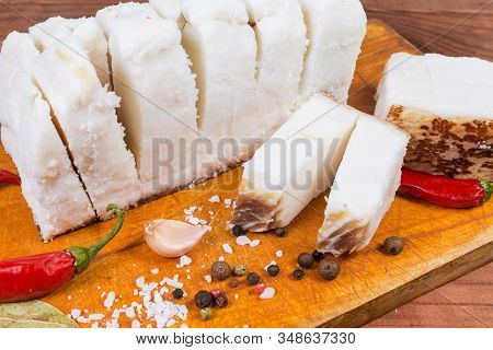 Pieces Of Partly Cut Salted Pork Fatback On Skin Lie On The Wooden Cutting Board Among The Some Spic