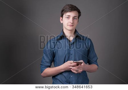Confident Handsome Young Man In Shirt With Rolled Sleeves Holding Smartphone And Looking At Camera I