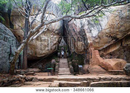 Sigiriya, Sri Lanka - 23 March 2017: Tourists Walking On Stairs Between Two Huge Orange Stones