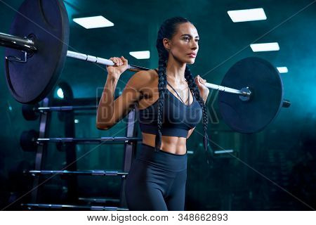 Side Crop Of Brunette Female Bodybuilder With Long Braids Doing Squats Using Barbell On Shoulders. S
