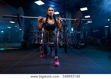 Front View Of Brunette Female Bodybuilder With Braids Doing Squats Using Barbell. Srtong Woman With 