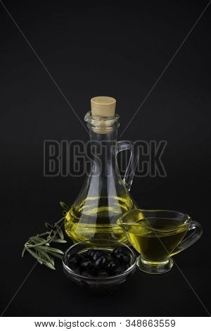 Olive Oil With Dark Olives On Black Background.